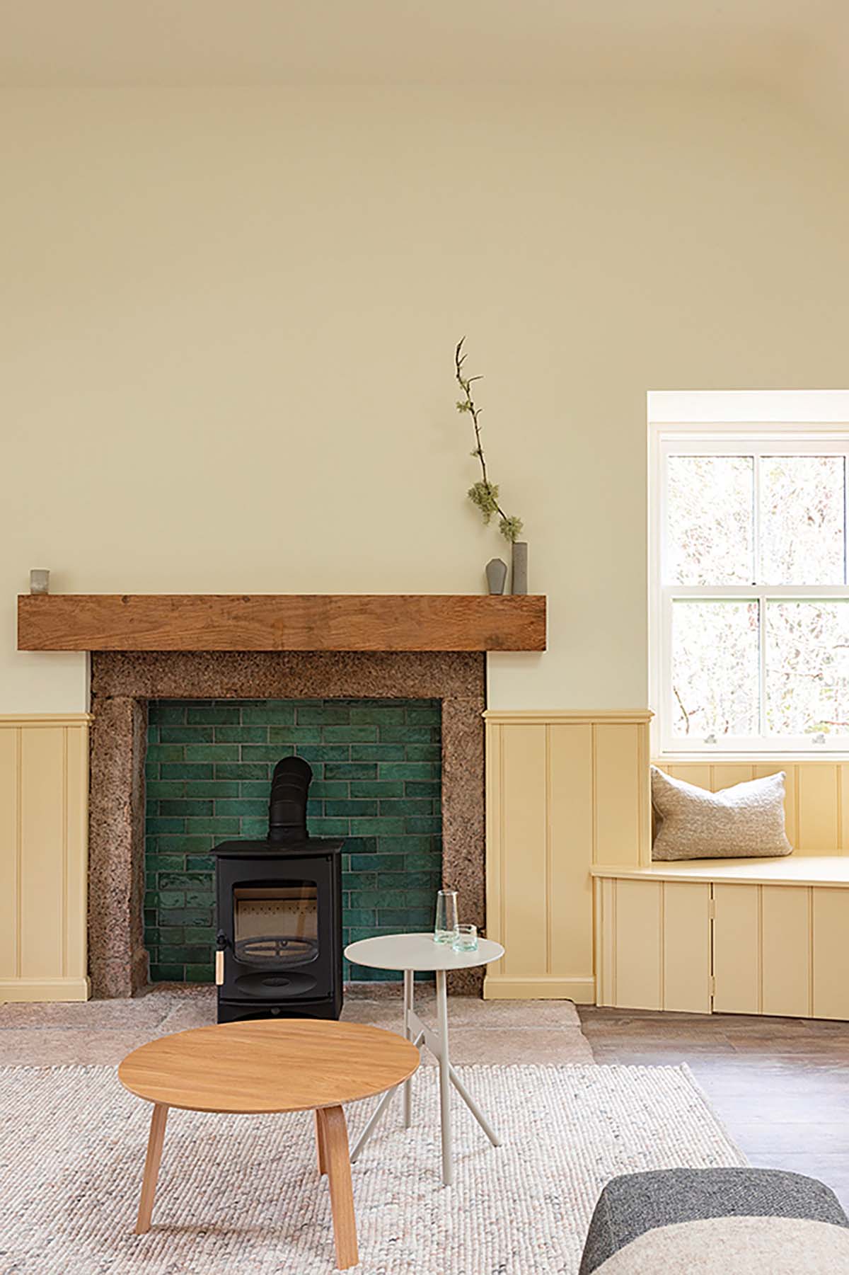 traditional fireplace with wooden mantles and raw stone surrounds and green tiling for character - framed by neutral wall panelling to brighten an otherwise dark feature