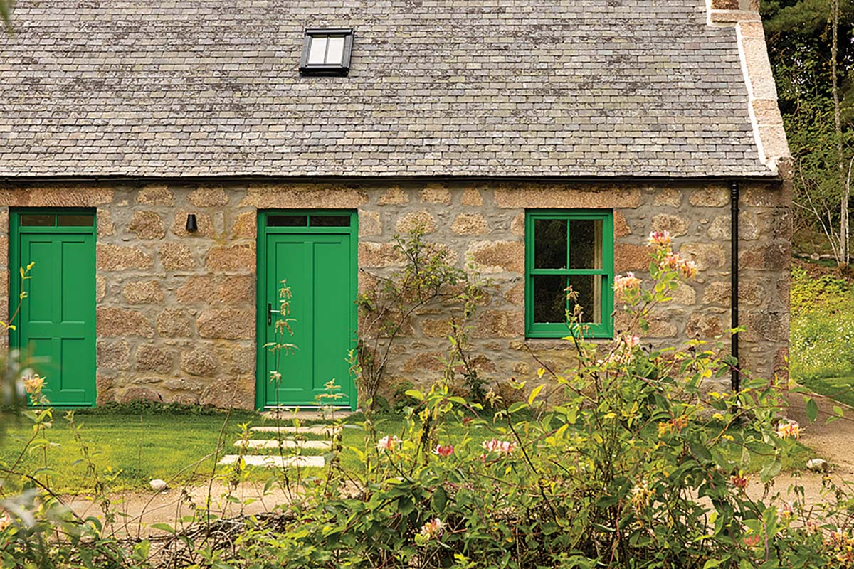 cottage original exterior for a schoolhouse build in aberdeenshire, scotland, by rachel walker architects. featuring green doors and windowpanes with grey slate roof and original stonework