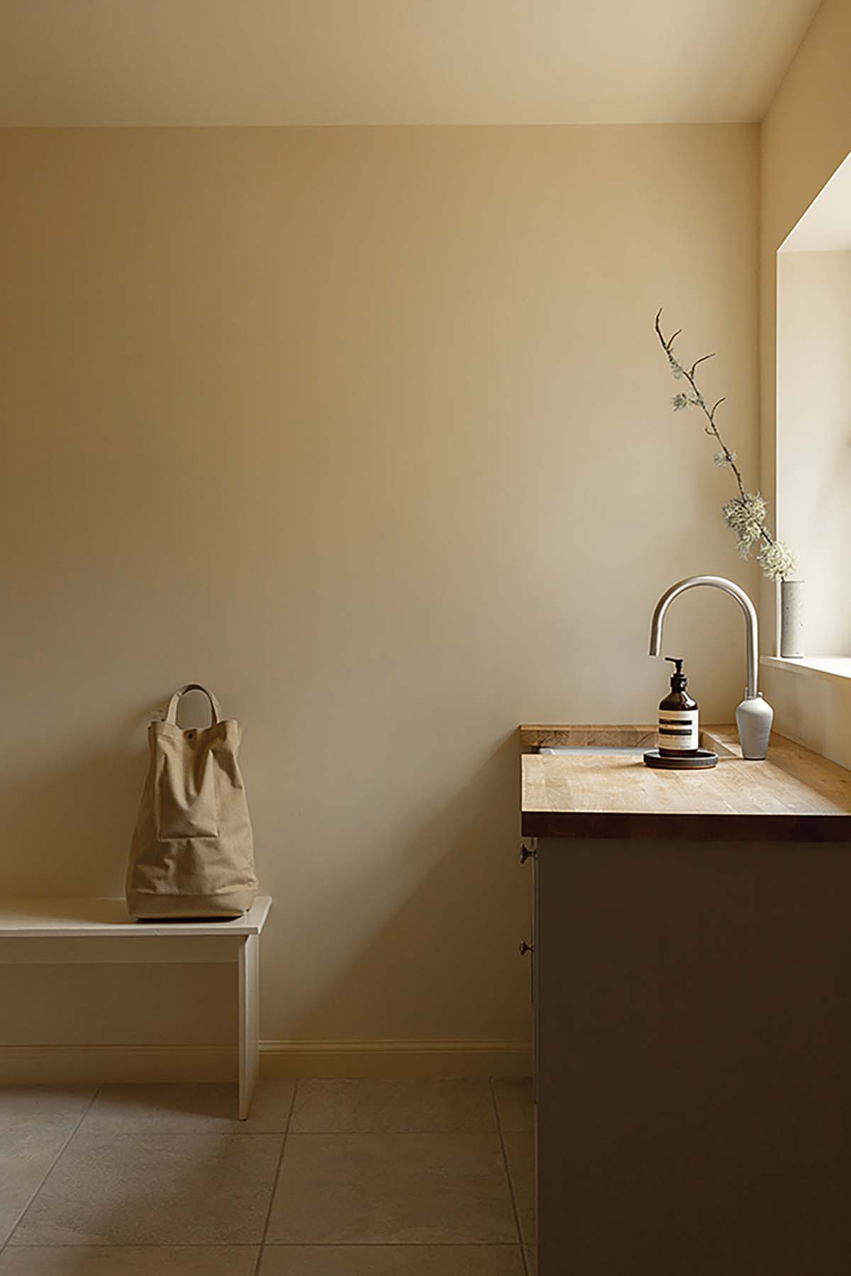 an elegant and understated sink and kitchen area, featuring aesop soap, canvas shoppers, sleek grey cabinetry and undermount sink