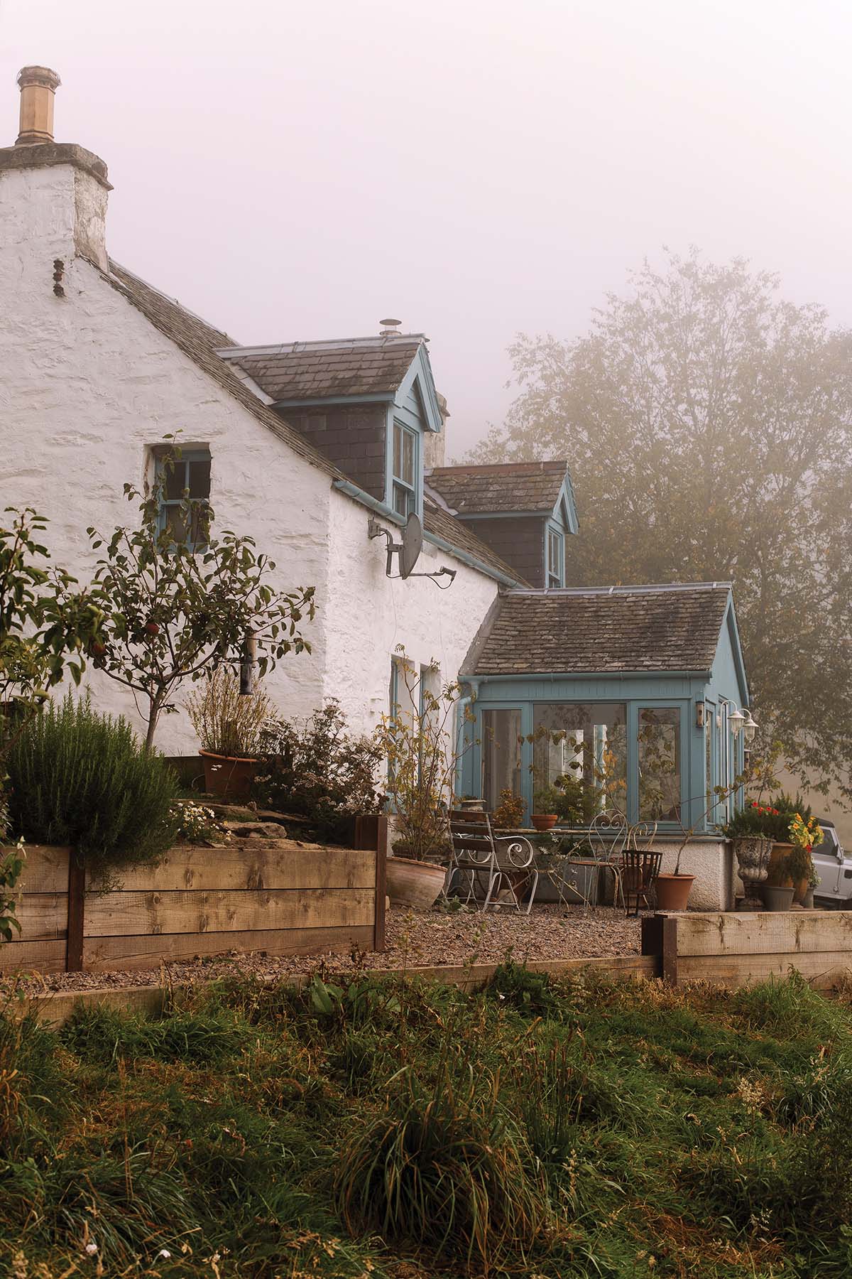 exterior or white cottage with adorable blue door in the hills of rural perthshire in scotland