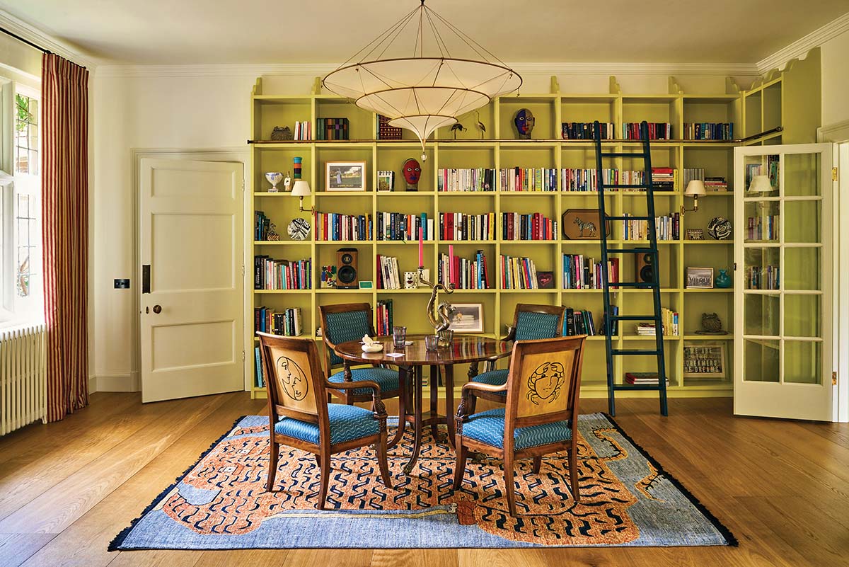 The French Empire chairs are decorated with each family member's star sign. Overhead hangs a Fortuny silk pendant. Studio Hollond designed the bookcases