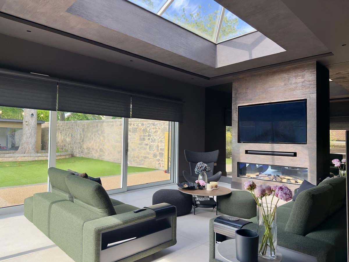 A living room in Scotland design by Valenco Surface Design featuring media wall and inset fireplace with sliding patio doors and a green couch