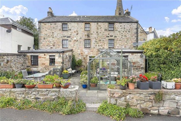 old stone townhouse in scotland with greenhouses and a summer room, with lots of plants and vegetable patches