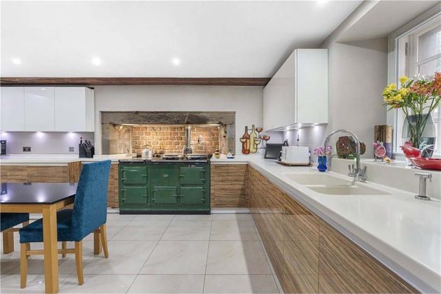 oak wood cabinets in a modern kitchen with white tiles, blue dining chairs and traditional green aga cooker stove