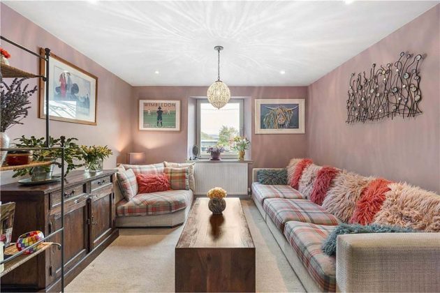pink living room with pendant lights, collage wall, vintage varnished coffee table, vintage walnut cabinets and grey and pink sofas