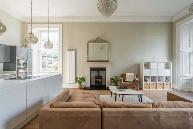 high-end homes for sale in Edinburgh; neutral boho living room scandi inspired style with black wood stove, brown sofas, brown carpets, round pendant lights and white radiators
