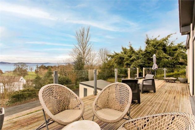 high-end homes for sale in Tanglewood; high-end homes for sale in Tanglewood; wooden balcony with rattan outdoor furniture and blue skies in scottish countryside
