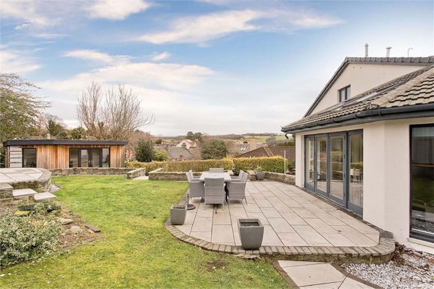 high-end homes for sale in Tanglewood; back garden patio with green grass and grey garden furniture