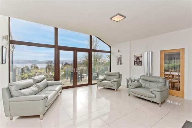high-end homes for sale in Tanglewood; white conservatory with oak wood beams and double doors and grey leather sofas and white floor tiles