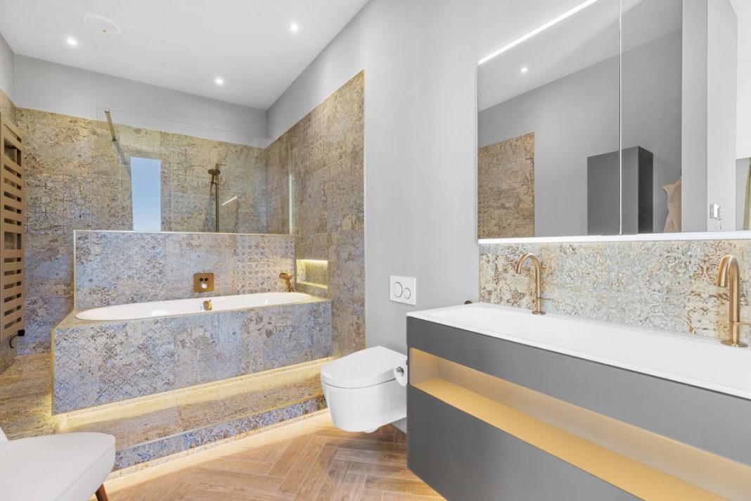 white stone bathroom with backlighting and underfloor heating, a big wall mirror over the white porcelain sink