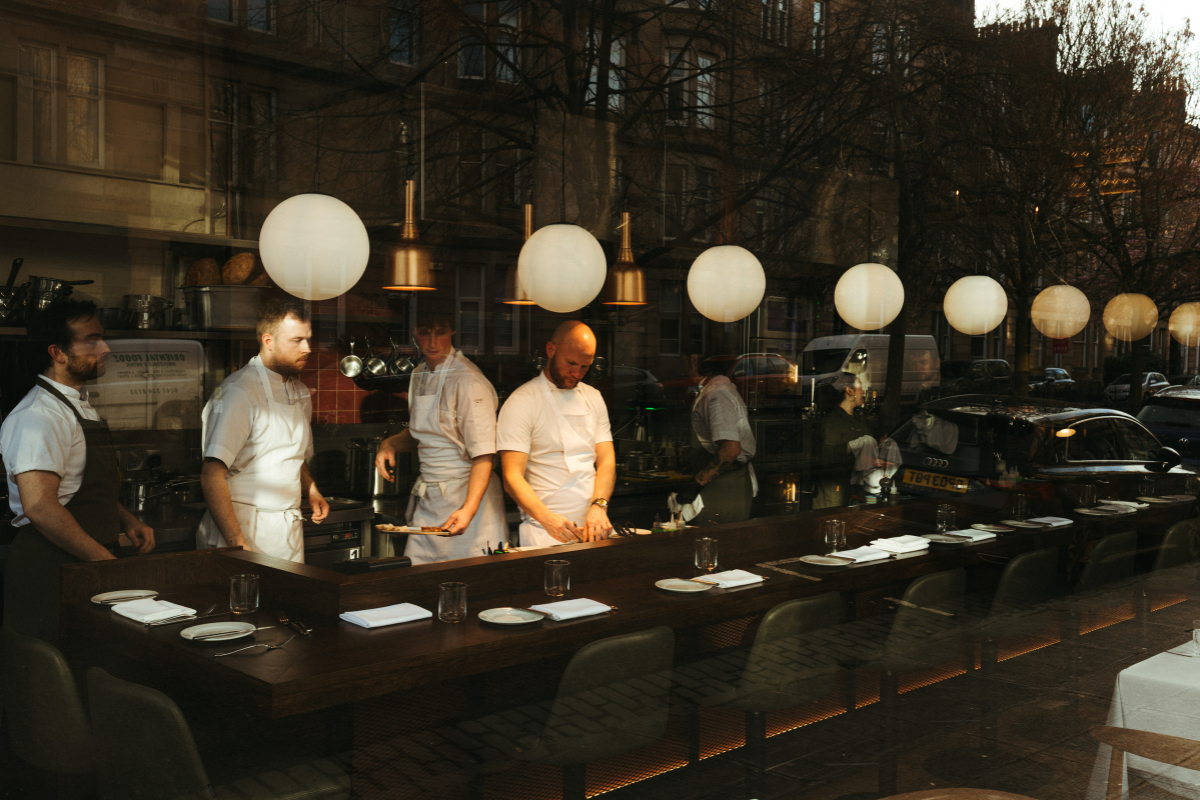 Chef director Colin Anderson and his team cooking in Brett open kitchen, framed by a counter dining area