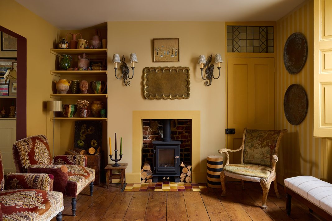 yellow living room with a black fireplace, wobbly mirror and red and white striped sofas