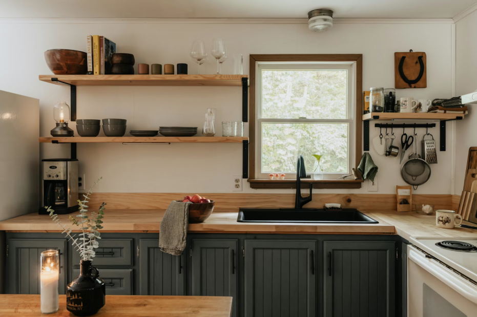 wooden kitchen wit blue cabinets and bookshelves above the sink