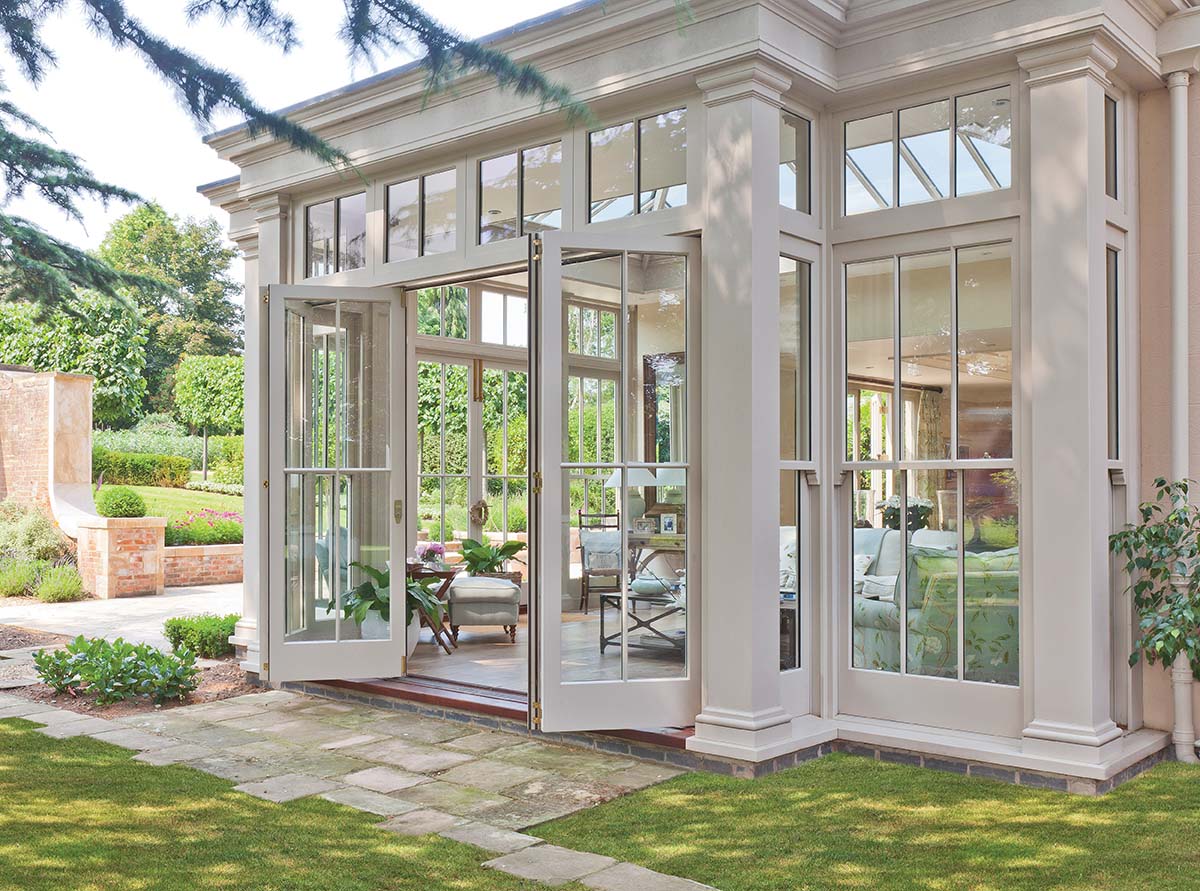 big white conservatory with big windows, a white patio and round tree