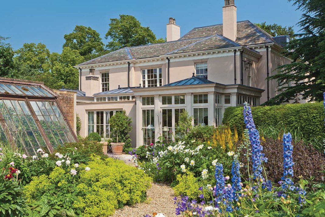 big garden with flowers, round bushes, a large patio and conservatory sunroom
