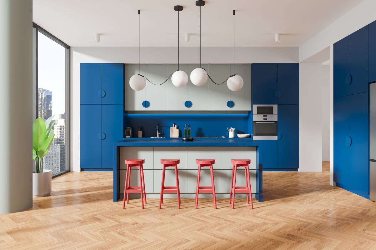 blue kitchen with pink bar stools and a white breakfast bar kitchen island and black pendant lighting