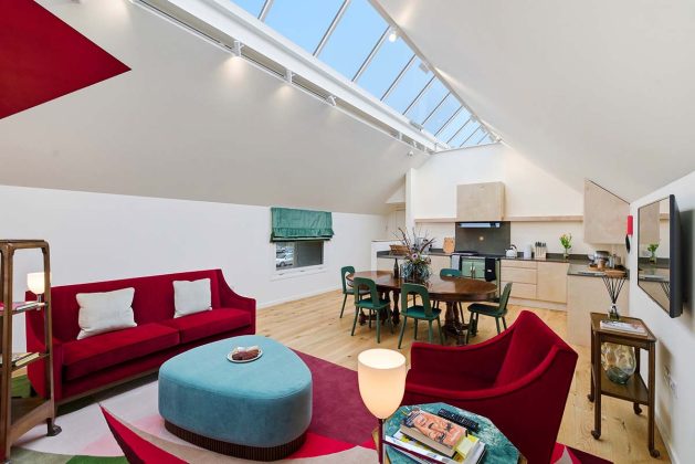 red living room furniture with skiylight and kitchen in a farmhouse design scheme