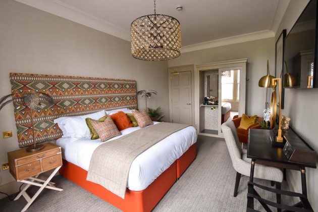 orange bed with wacky patterned Morocco headboard and grey chairs