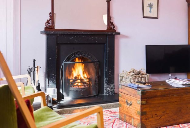 pink living room with fireplace and green chairs, one of Scotland's best luxury hotels, cottages and cabins