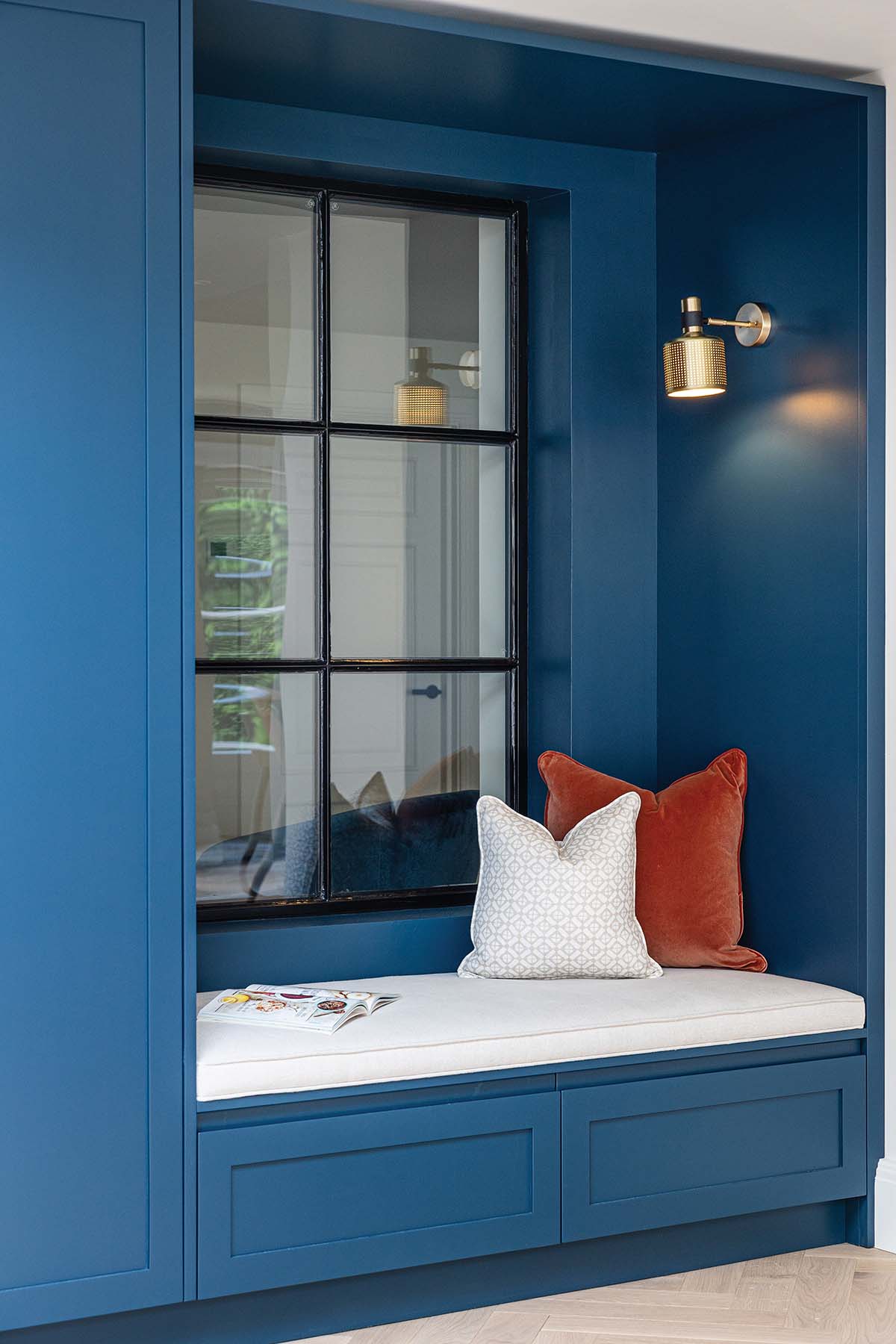 reading nook with blue walls and a white cushion; a feature on designing with glass