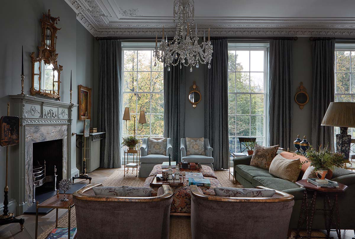 designed by Hubert Zandberg: glass chandelier in a city townhouse, with blue sofas, window walls, ornate blue fireplace and pink carpets