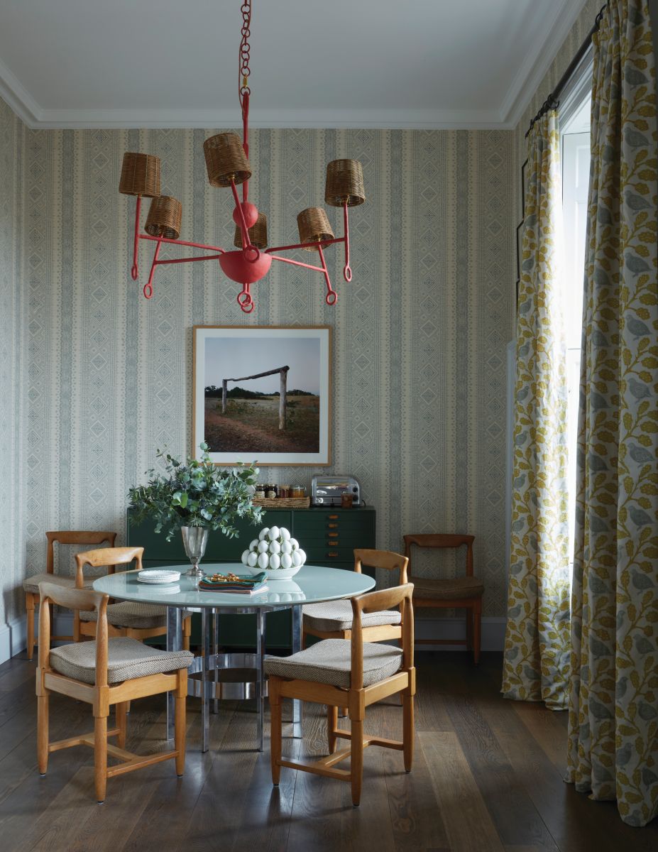 designed by Hubert Zandberg: red pendant lights, blue dining table, wooden dining chairs, patterened wallpaper, green curtains