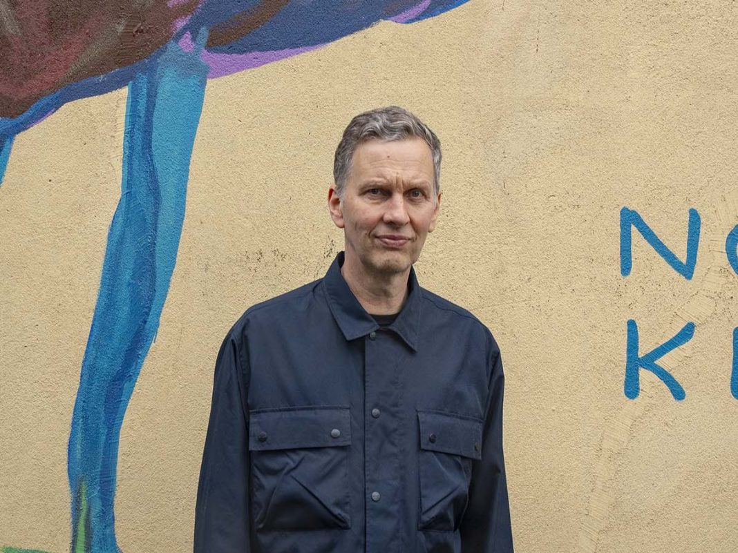 David Shrigley stands in front of his largest painting to date: a huge cockerel on the walls of Cubitt's new space for spectacle making and events