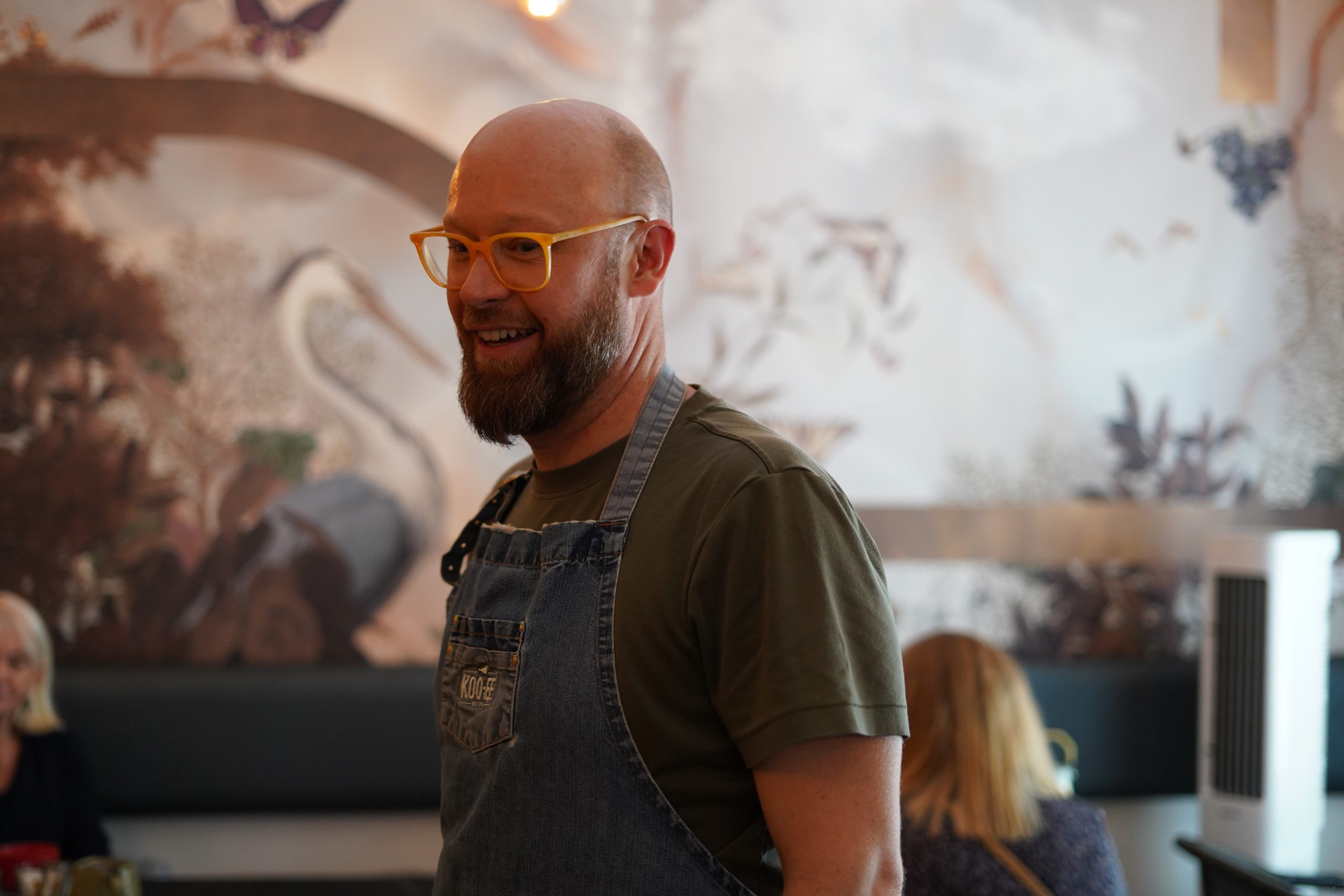David Gallagher stands infront of wall murals in the studio