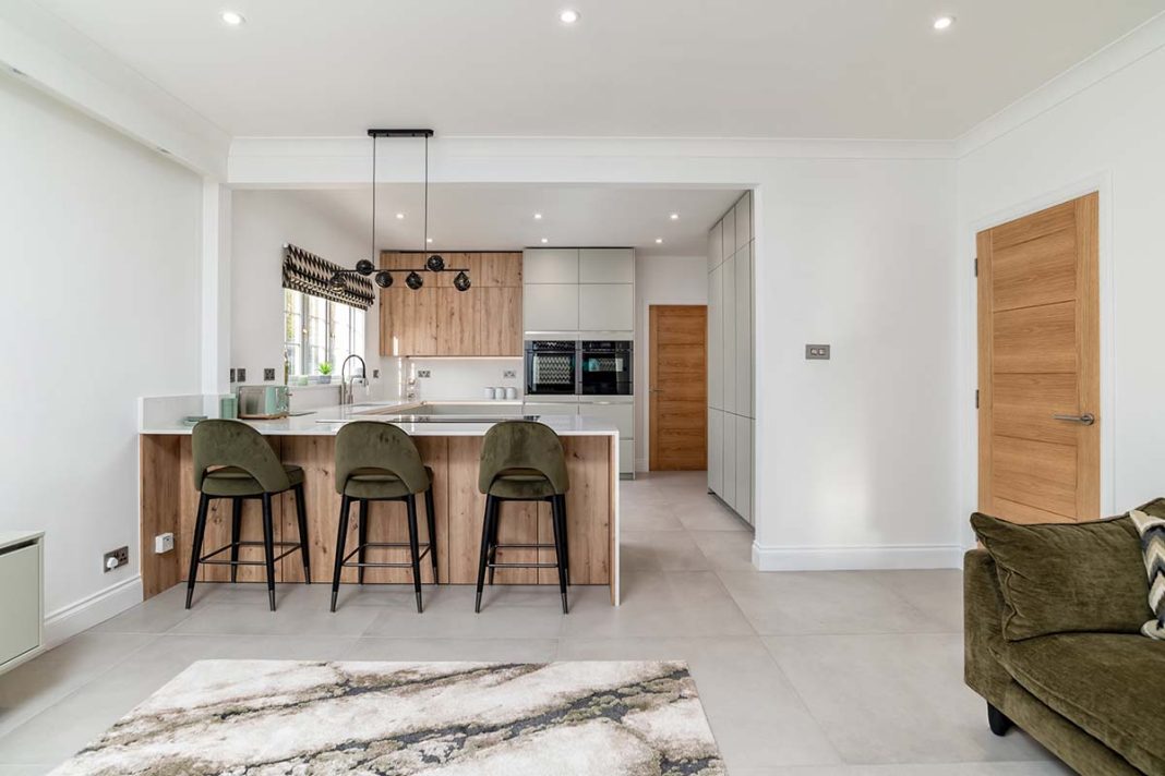 white kitchen with oak offsets and green chairs