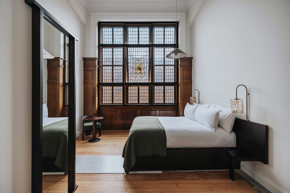 walnut flooring, stain glass windows and green bed frame and headboard in a private room at arthouse glasgow