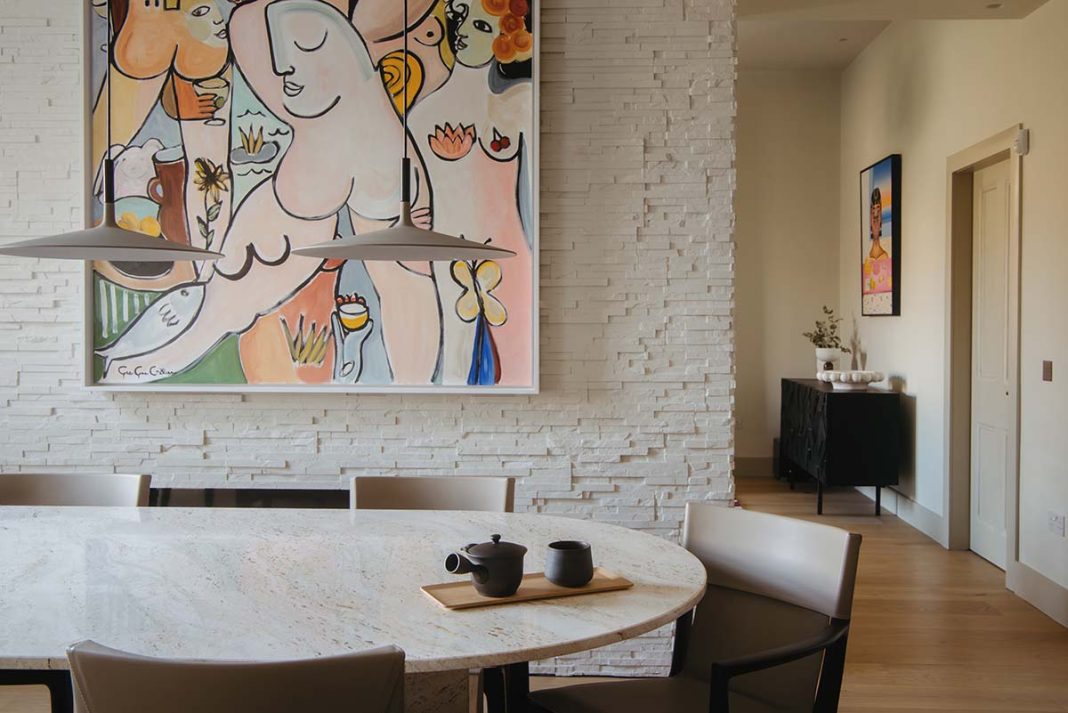 a colourful room filled with artwork and white painted exposed stone walls