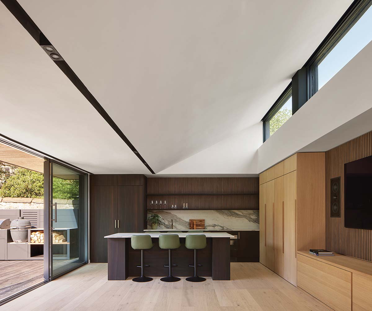 green chairs in an oak kitchen with sliding doors onto patio and high tech kitchen equipment